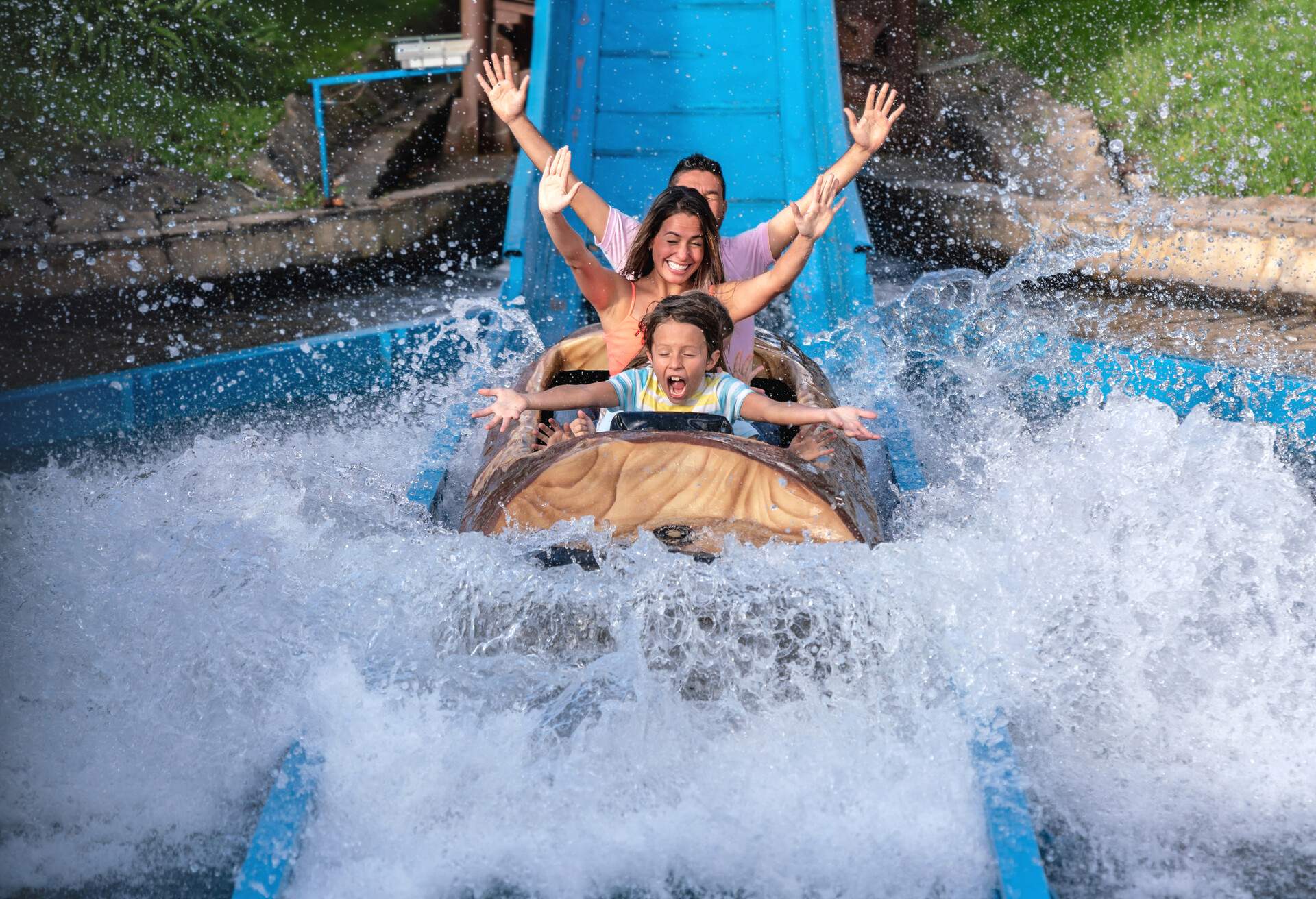 Happy family having fun in an amusement park riding on a fun water ride - lifestyle concepts