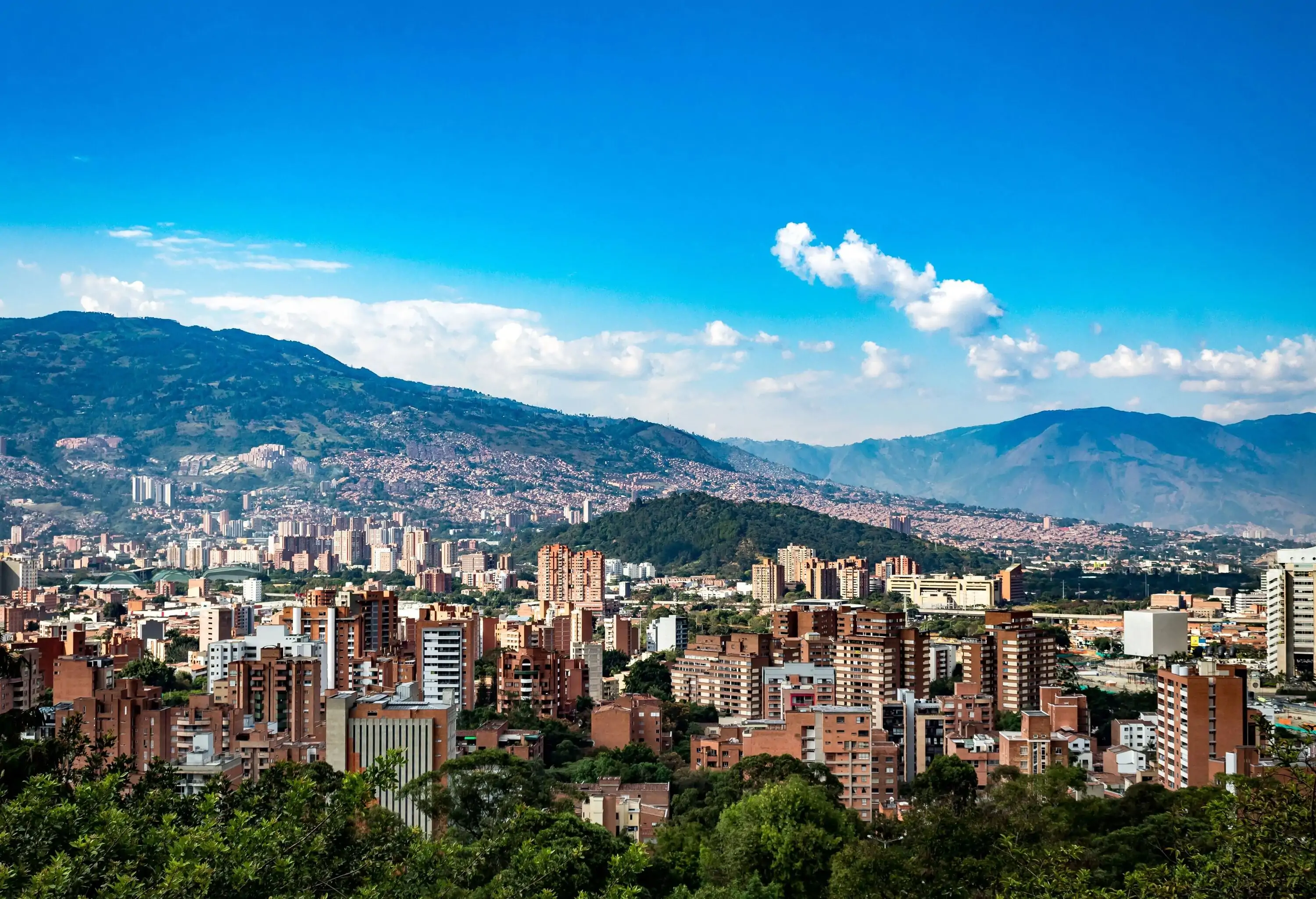A cluster of high-rise buildings in a city surrounded by mountains.