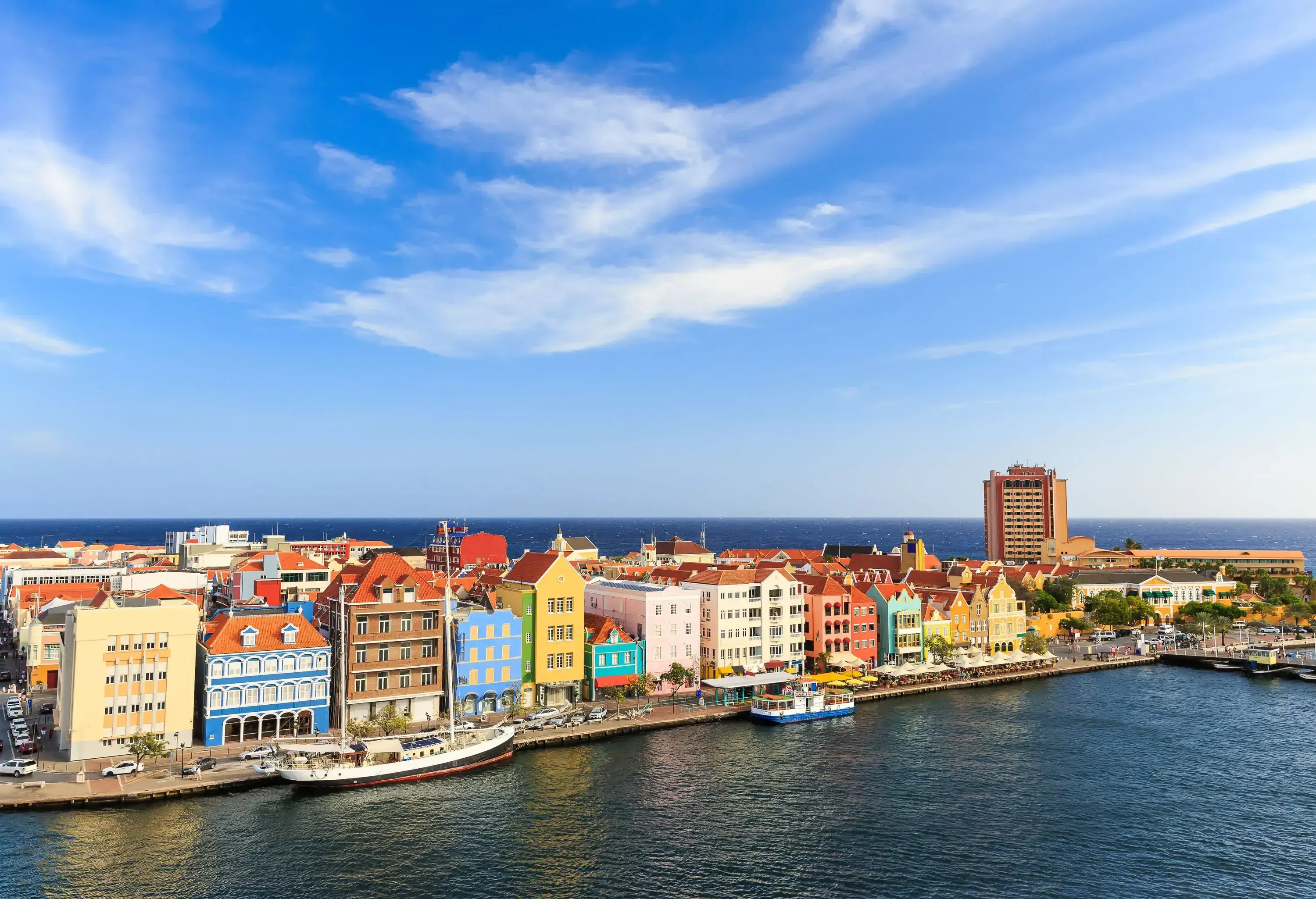 A picturesque array of colourful buildings stands proudly by the coast, with vessels gracefully moored nearby.